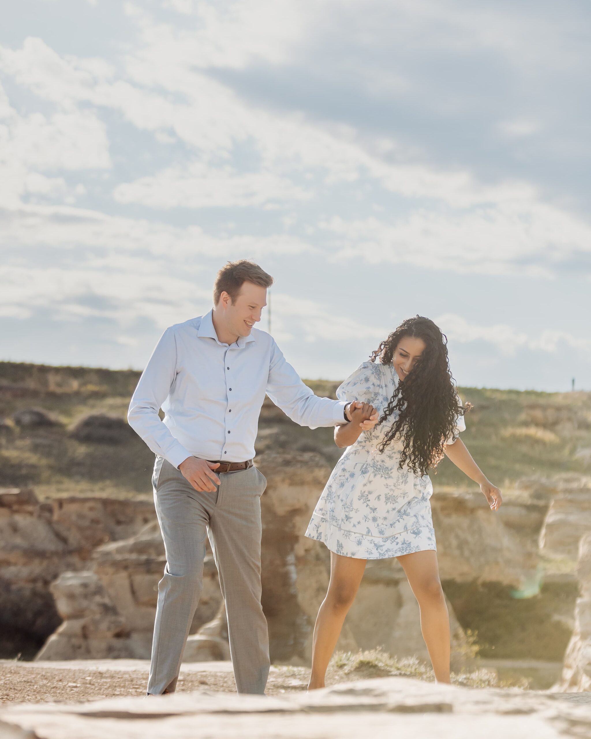 Couple playfully walking along hoodoos in Southern Alberta.