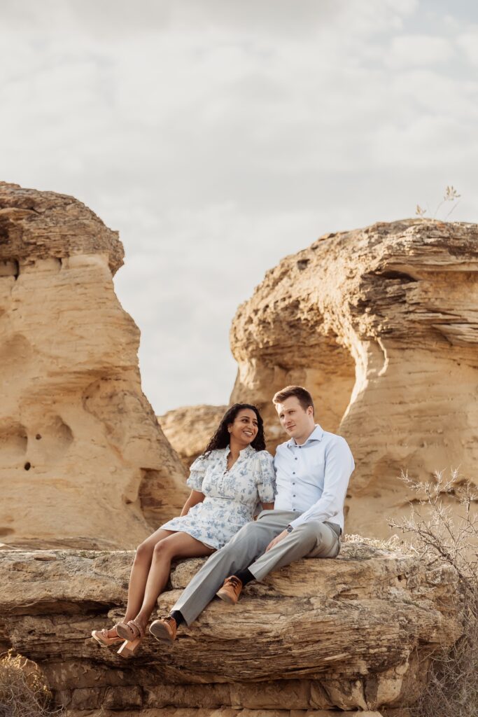 Couple sitting on a hoodoo in Writing-on-Stone Provincial Park.