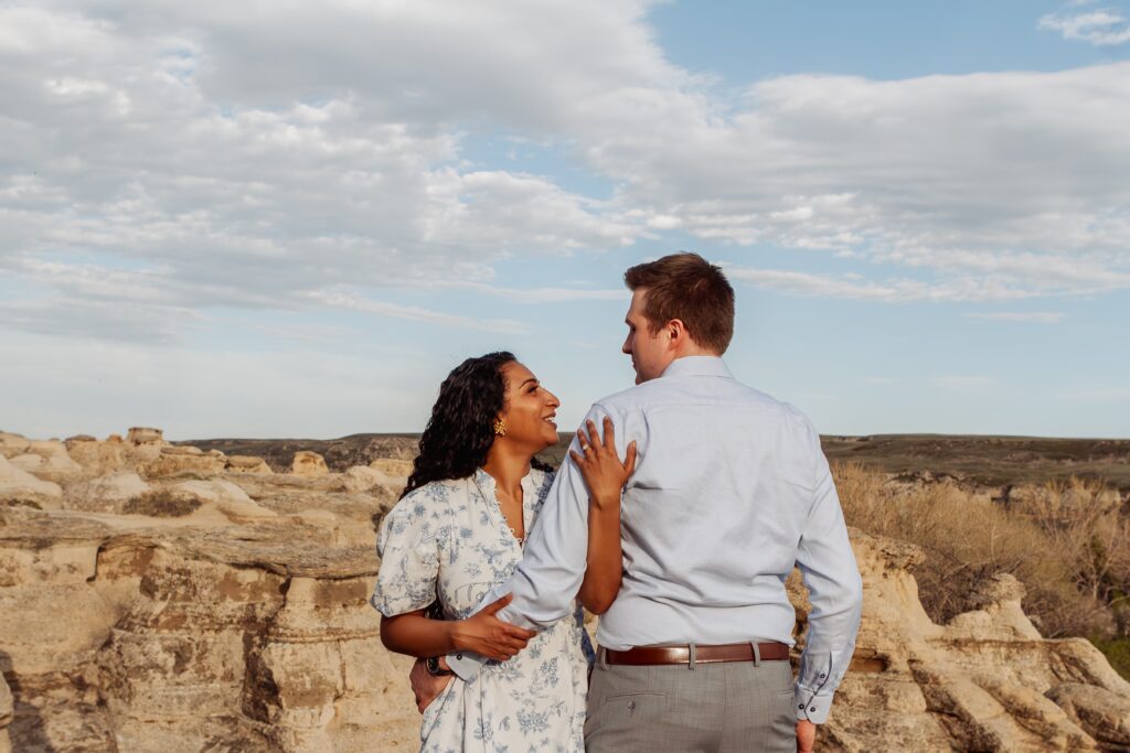 Couple embracing with hoodoos in the background at Writing-on-Stone Provincial Park.